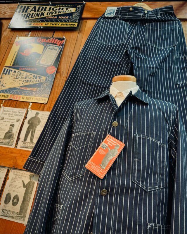 Lot No. HD15647
“HEADLIGHT 8oz. SPECIAL WOVEN STRIPE DENIM WORK COAT”
This season features woven stripe denim items, which were originally advertised in 1914 and are now almost non-existent in vintage collections. Rather than a print, the stripes are woven into the fabric, clearly positioning it as a competitor to Stifel’s Wabash stripes. An analysis was conducted using a fabric swatch attached to a novelty notebook distributed in retail stores. The fabric is made from No. 10 cotton thread in three colors—indigo, natural, and charcoal—woven in a left-hand twill.

The design is a work coat that retains elements of a sack coat, with a silhouette featuring an A-line and no stand collar. Before the introduction of special sewing machines, features like eyelet buttonholes and bar-tacks were not used. All buttons are changeable, and the collar and cuffs can be adjusted using two buttonholes. The pockets are attached with double stitching, sewn twice using a single-needle machine.
 
#SugarCaneDenim #ToyoEnterprise #HeadlightOveralls #WovenStripe #MadeinJapan