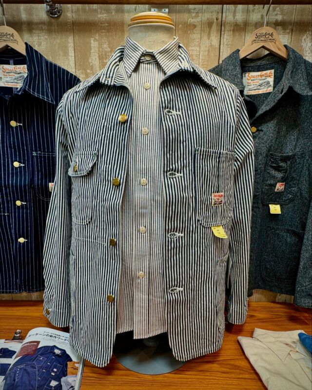 Lot No. SC15656
“11oz. HICKORY STRIPE WORK COAT”
A simple yet vintage-inspired work coat from the post-World War II era, featuring classic store-brand details like unique asymmetrical-shaped chest pockets. This model includes a collar band, which was later omitted, with a flap pocket on the right chest and a 3-in-1 pocket on the left chest. The large waist pockets have reinforced linings, and an interior pocket is added on the right chest. Triple-needle stitching is used on the shoulders, sides, and armholes for extra durability.
　　　　　 
#SugarCaneDenim #ToyoEnterprise #HickoryStripe #WorkCoat #MadeinJapan